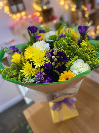 Out in the Woods - A enchanting handtied in water presented in a gift box , created using the fresh blooms of the day in yellow, purple and white with complementary foliage.