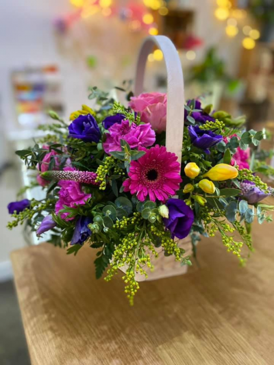Always Enchanting - A delightful basket arrangement, created using the fresh blooms of the day in a mix of pink, purple and yellow with complementary foliage.