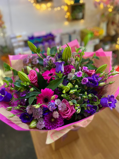 Pixies Perfection - An enchanting handtied in water presented in a gift box, created using the fresh blooms of the day in pink and purple with complementary foliage.